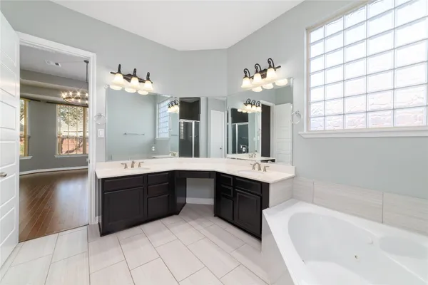 a spacious bathroom with a tub double sink and mirror