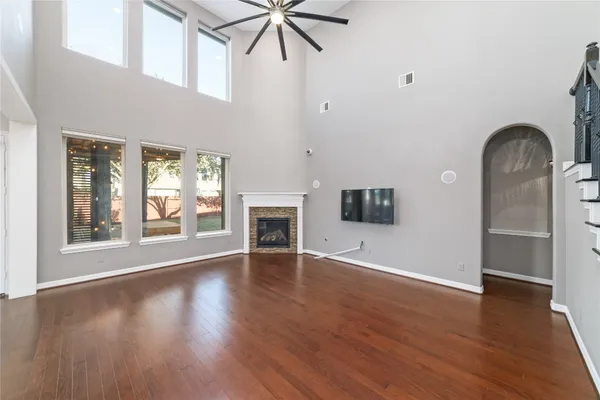 an empty room with wooden floor a ceiling fan and windows