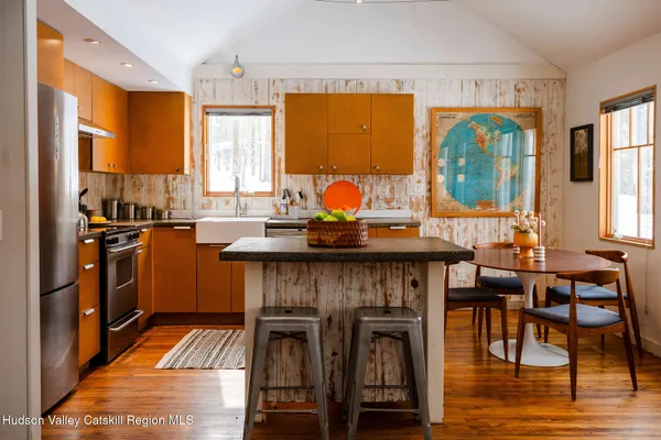 a kitchen with stainless steel appliances granite countertop a stove top oven a sink a dining table and chairs with wooden floor