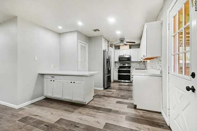 a kitchen with white cabinets and appliances