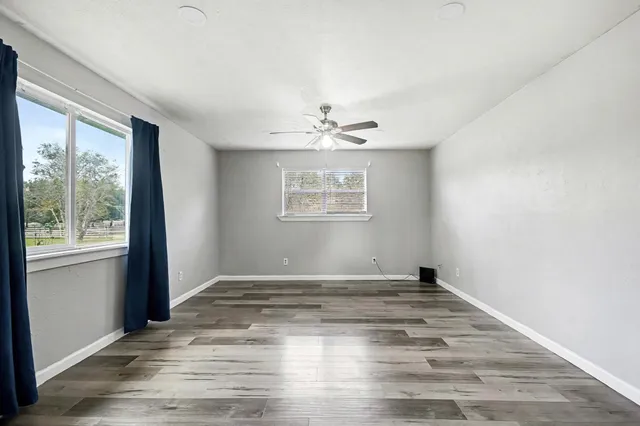 an empty room with wooden floor and windows