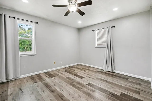 a view of empty room with wooden floor and fan