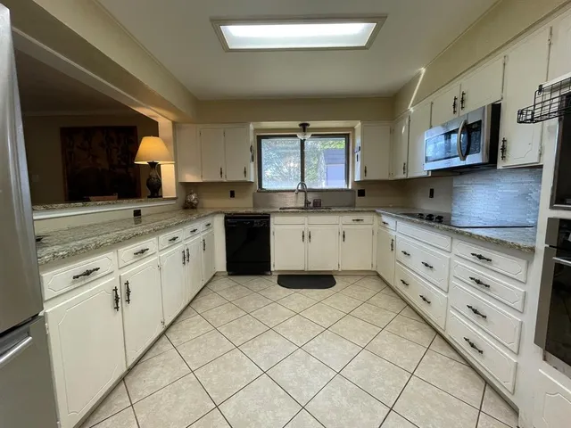 a kitchen with granite countertop white cabinets white stainless steel appliances with a sink and dishwasher