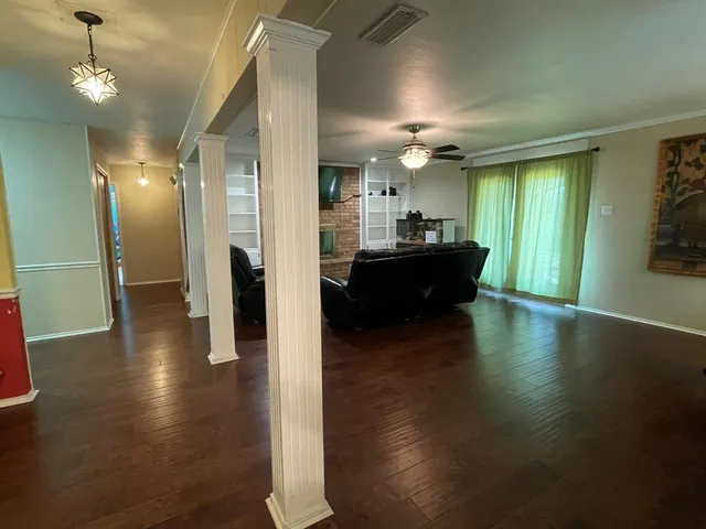 a view of a hallway with wooden floor and a kitchen