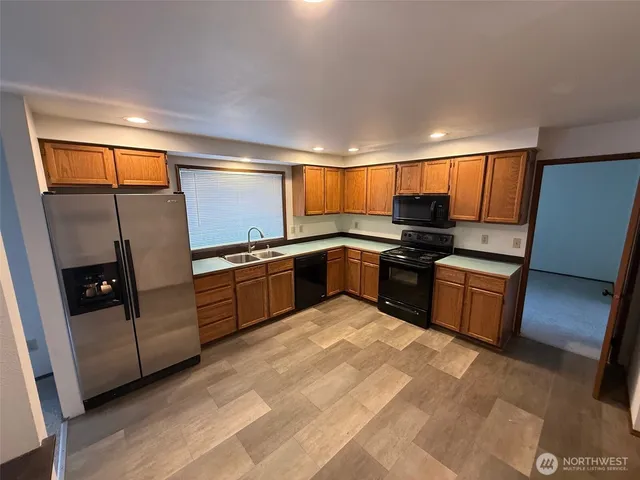 a kitchen with granite countertop stainless steel appliances a sink a counter top space and cabinets