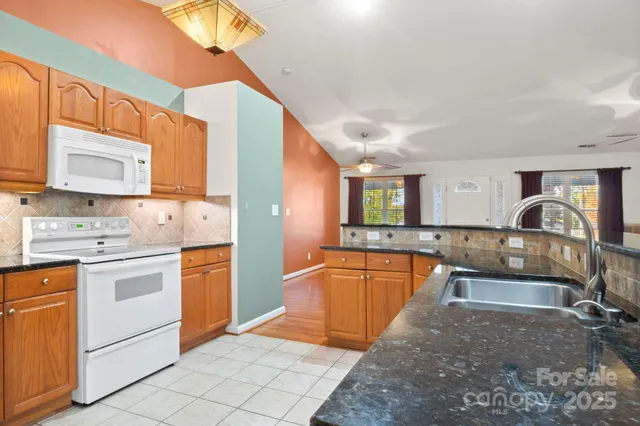 a large kitchen with stainless steel appliances granite countertop a sink and cabinets