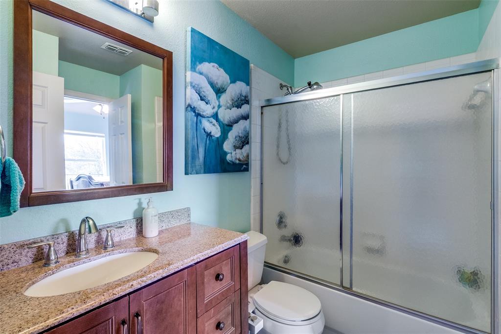 1802 Benedict Court Rowlett, TX 75088 - Photo 19 of 30 a bathroom with a granite countertop sink toilet a mirror a vanity and shower