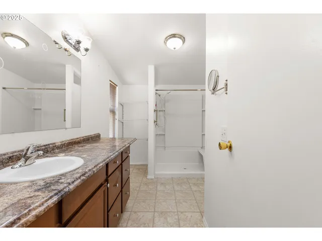 a bathroom with a granite countertop sink a mirror and shower