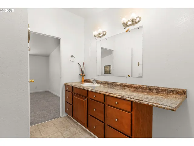 a bathroom with a granite countertop sink and a mirror