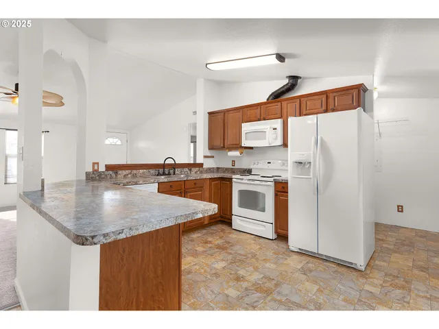 a kitchen with kitchen island a sink a stove a refrigerator and white cabinets