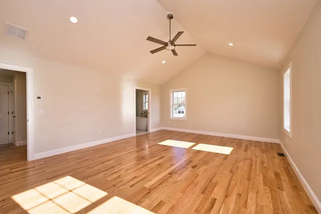 a view of empty room with wooden floor and fan