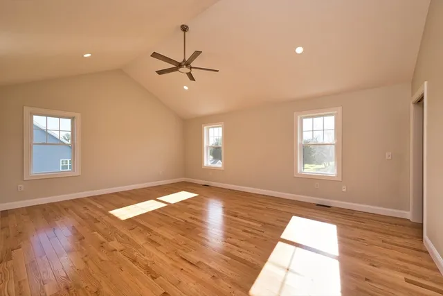 a view of empty room with wooden floor and fan