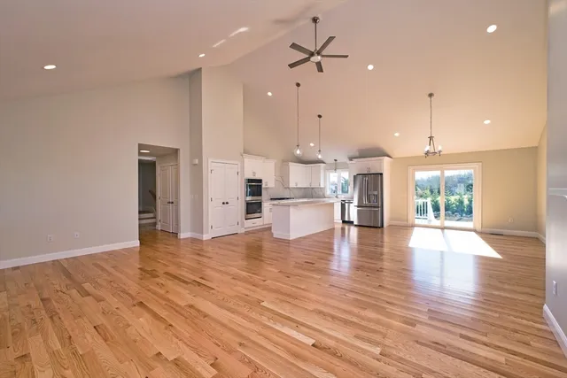 a view of kitchen with stainless steel appliances granite countertop a refrigerator a stove and a wooden floors