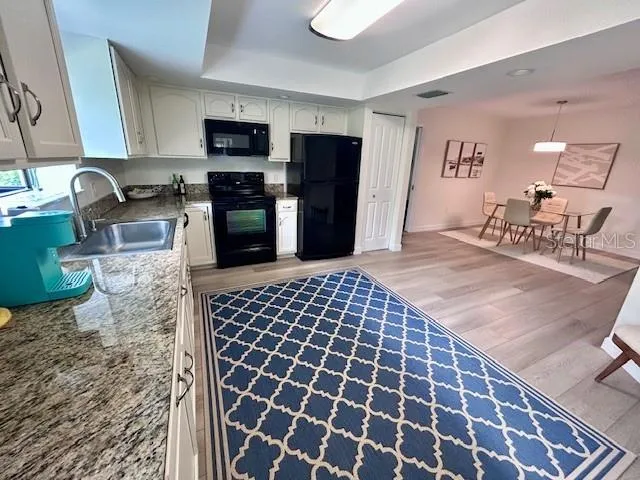 a kitchen with granite countertop a stove a sink and a microwave