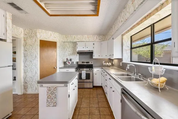 a kitchen with a sink dishwasher a stove and white cabinets with wooden floor