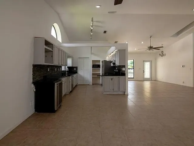 a kitchen with granite countertop a refrigerator stove top oven and sink