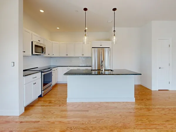 a kitchen with kitchen island a counter top space a sink stainless steel appliances and cabinets