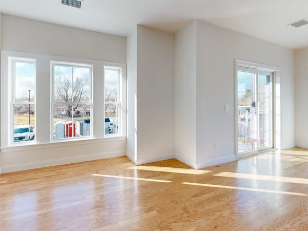 an empty room with wooden floor and windows