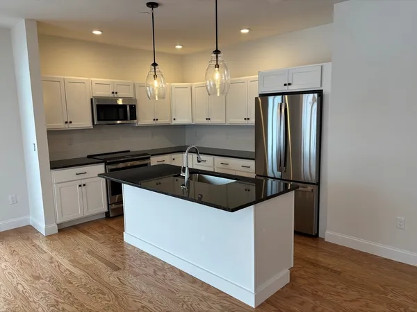 a kitchen with stainless steel appliances granite countertop a sink a stove and a refrigerator