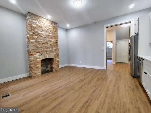 an empty room with wooden floor and fireplace