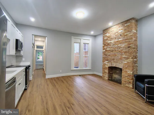 an empty room with wooden floor fireplace and windows