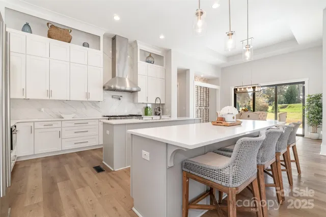 a kitchen with stainless steel appliances kitchen island granite countertop a table chairs and a refrigerator