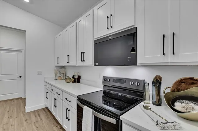 a kitchen with stainless steel appliances granite countertop a sink dishwasher a refrigerator and white cabinets with wooden floor