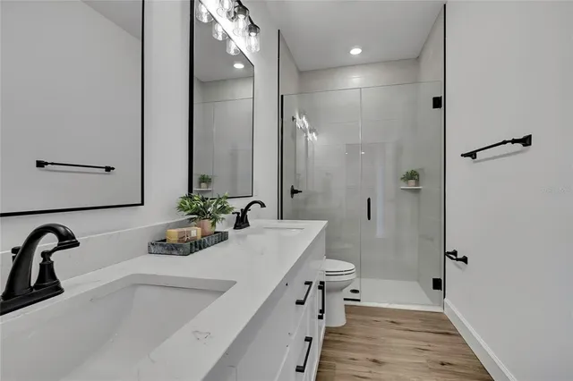 a bathroom with a sink a toilet a mirror a bathtub and shower