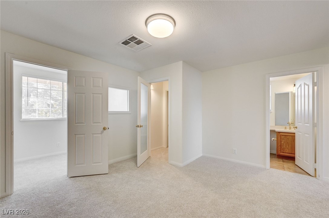 2955 El Camino Road Las Vegas, NV 89146 - Photo 63 of 99 Unfurnished bedroom featuring light carpet, ensuite bathroom, and a textured ceiling