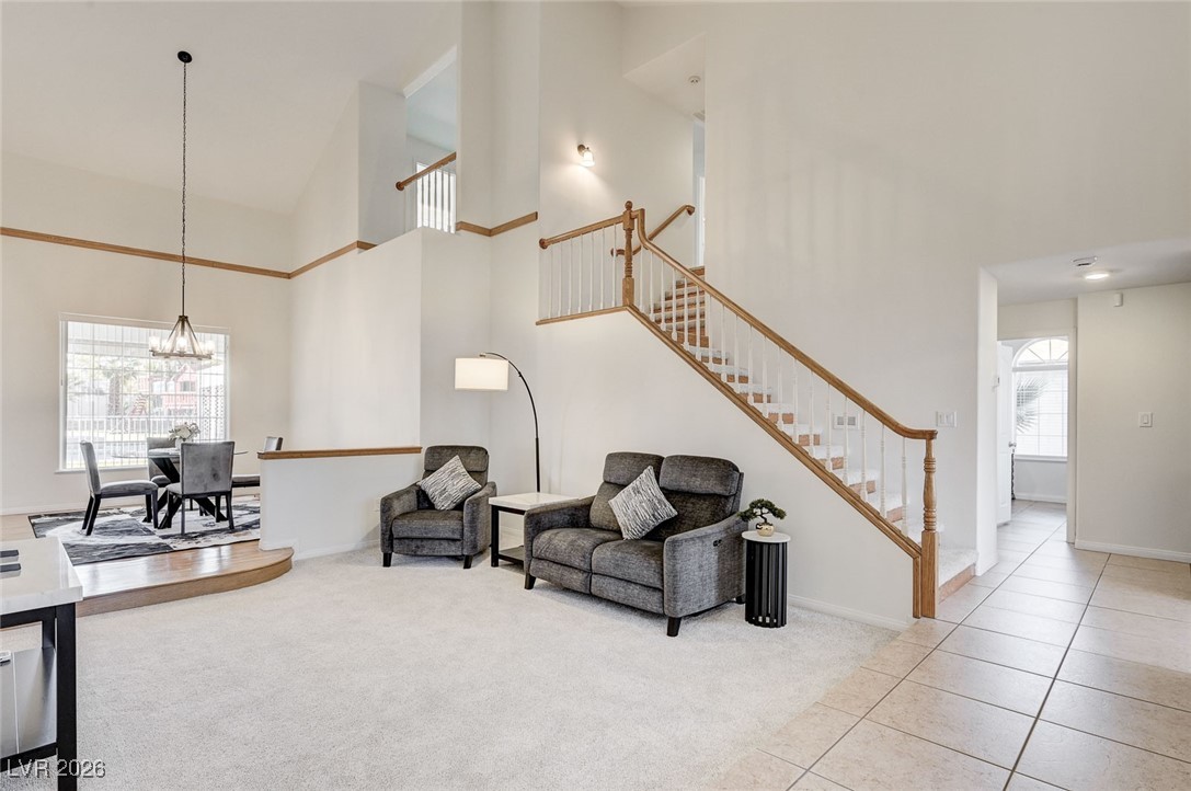 2955 El Camino Road Las Vegas, NV 89146 - Photo 35 of 99 Living room featuring high vaulted ceiling, light colored carpet, a chandelier, stairway, and light tile patterned floors