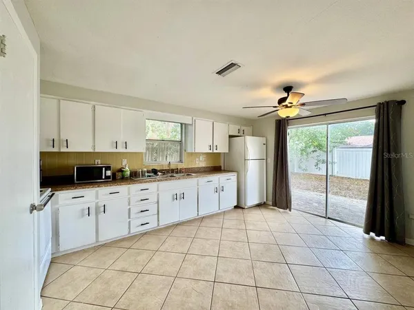 a large white kitchen with cabinets a sink a window and stainless steel appliances