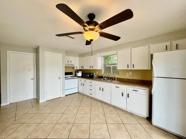 a kitchen with stainless steel appliances granite countertop a refrigerator a sink a stove and white cabinets