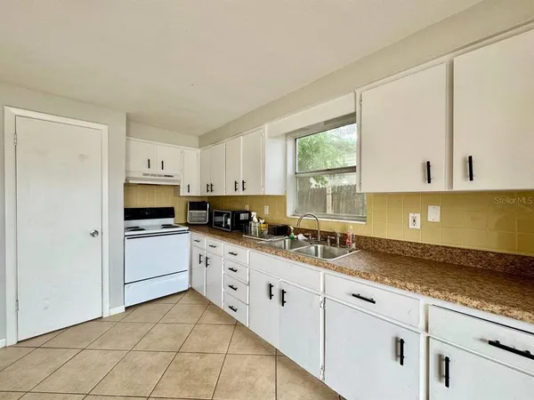 a kitchen with granite countertop white cabinets a sink a window and stainless steel appliances