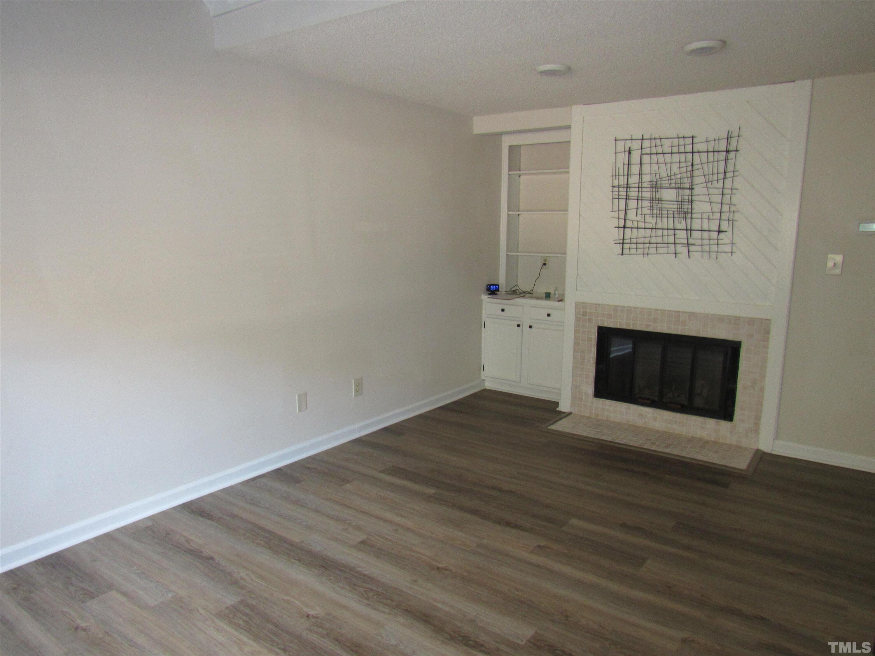 4309 Hunters Club Drive, Unit 4309 Raleigh, NC 27606 - Photo 6 of 35 an empty room with wooden floor and fireplace