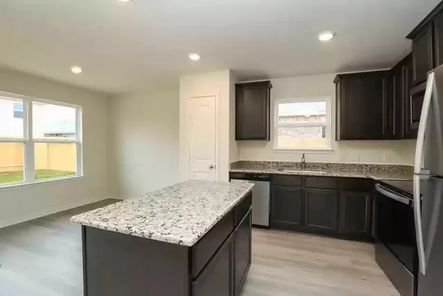 a kitchen with granite countertop kitchen island stainless steel appliances a sink stove and cabinets