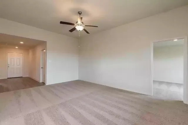 a view of an empty room with a chandelier fan