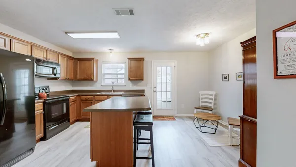 a kitchen with granite countertop a stove top oven a sink dishwasher a dining table and chairs with wooden floor