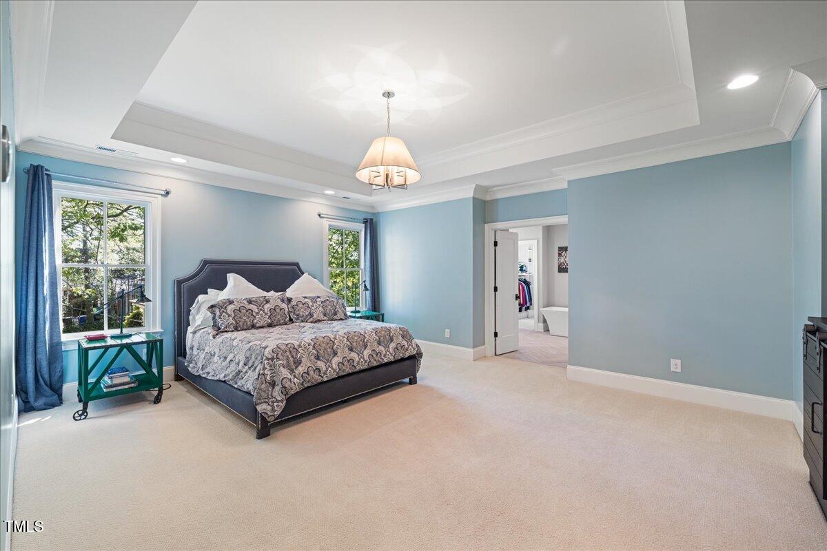 3513 Bellevue Road Raleigh, NC 27609 - Photo 29 of 61 a spacious bedroom with a large bed chandelier and a window