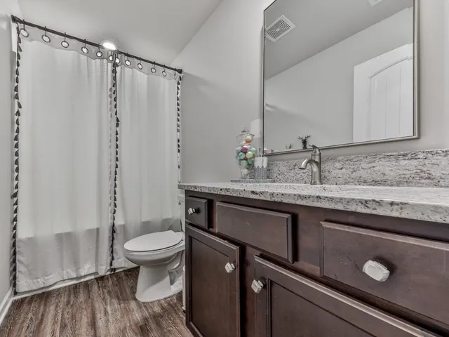 a bathroom with a sink a toilet a mirror and shower