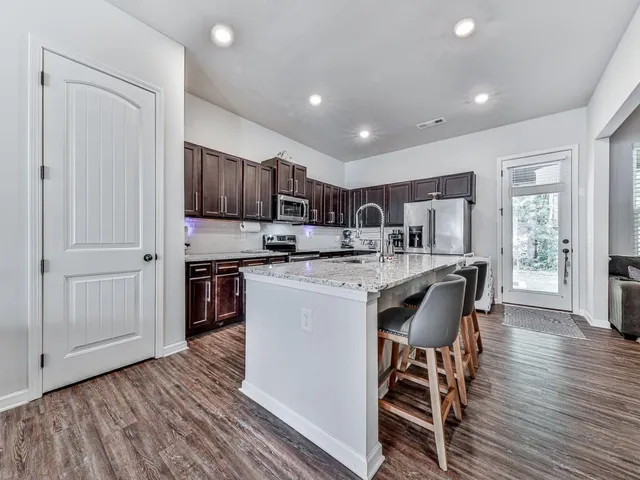 a kitchen with stainless steel appliances granite countertop a table chairs sink and cabinets