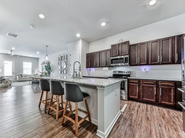 a kitchen with stainless steel appliances granite countertop wooden floors a stove top oven a sink and dishwasher