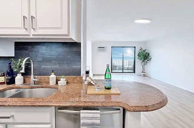a kitchen with granite countertop a sink a stove and cabinets