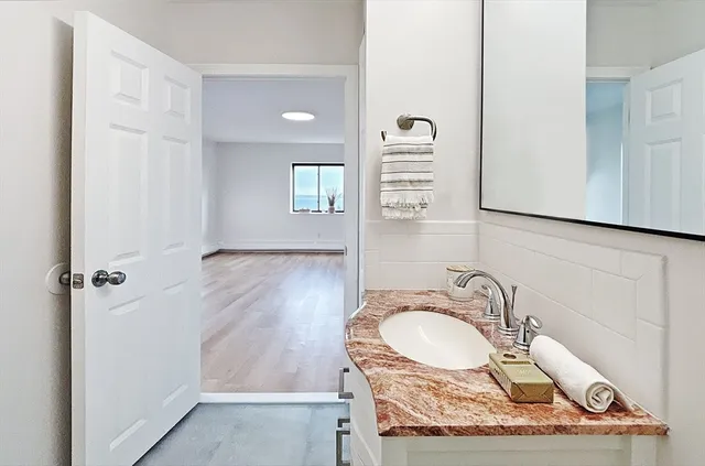 a bathroom with a granite countertop sink a mirror and shower