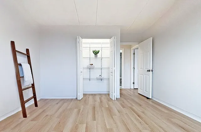 a view of an empty room with wooden floor and a bathroom