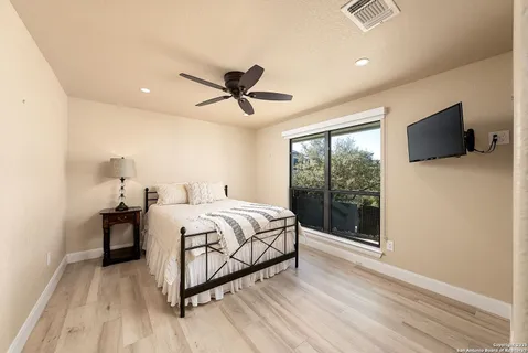 a bedroom with a large bed and a flat tv screen on dresser