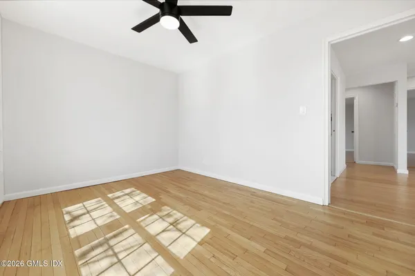 a view of a big room with wooden floor and windows