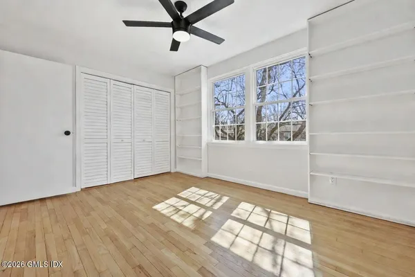 a view of empty room with wooden floor and fan