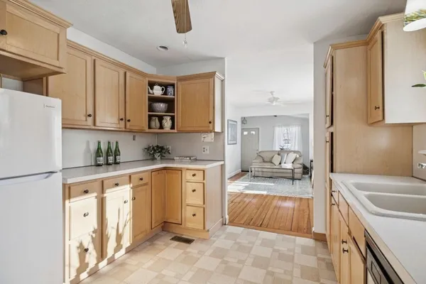 a large kitchen with granite countertop a sink a stove top oven a refrigerator a counter space and cabinets