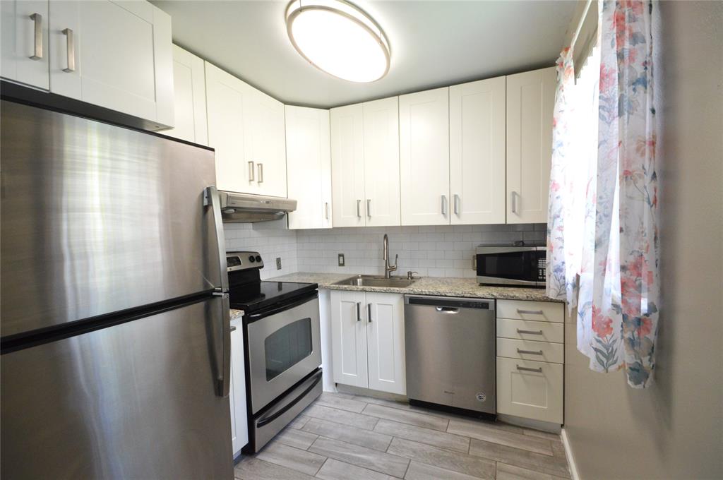 144 Mansfield D, Unit 144 Boca Raton, FL 33434 - Photo 9 of 37 a kitchen with stainless steel appliances granite countertop a refrigerator a sink dishwasher a stove and white countertops with wooden floor