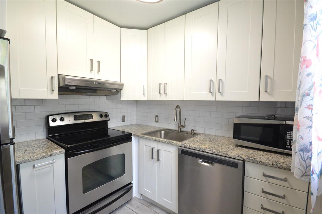 144 Mansfield D, Unit 144 Boca Raton, FL 33434 - Photo 10 of 37 a kitchen with granite countertop white cabinets and appliances